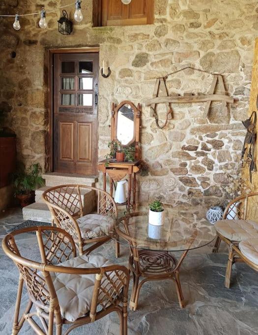 a room with a table and chairs and a stone wall at O lar de Cabanas in Brion