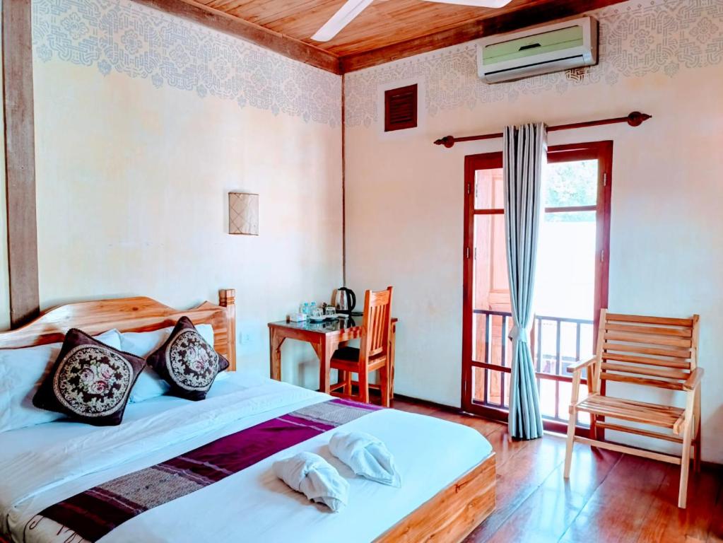 a bedroom with a bed and a desk and a window at Ireenkevin guesthouse in Luang Prabang