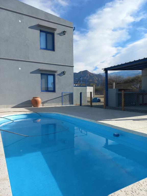 une grande piscine bleue devant une maison dans l'établissement Departamentos La Justina, à Cafayate