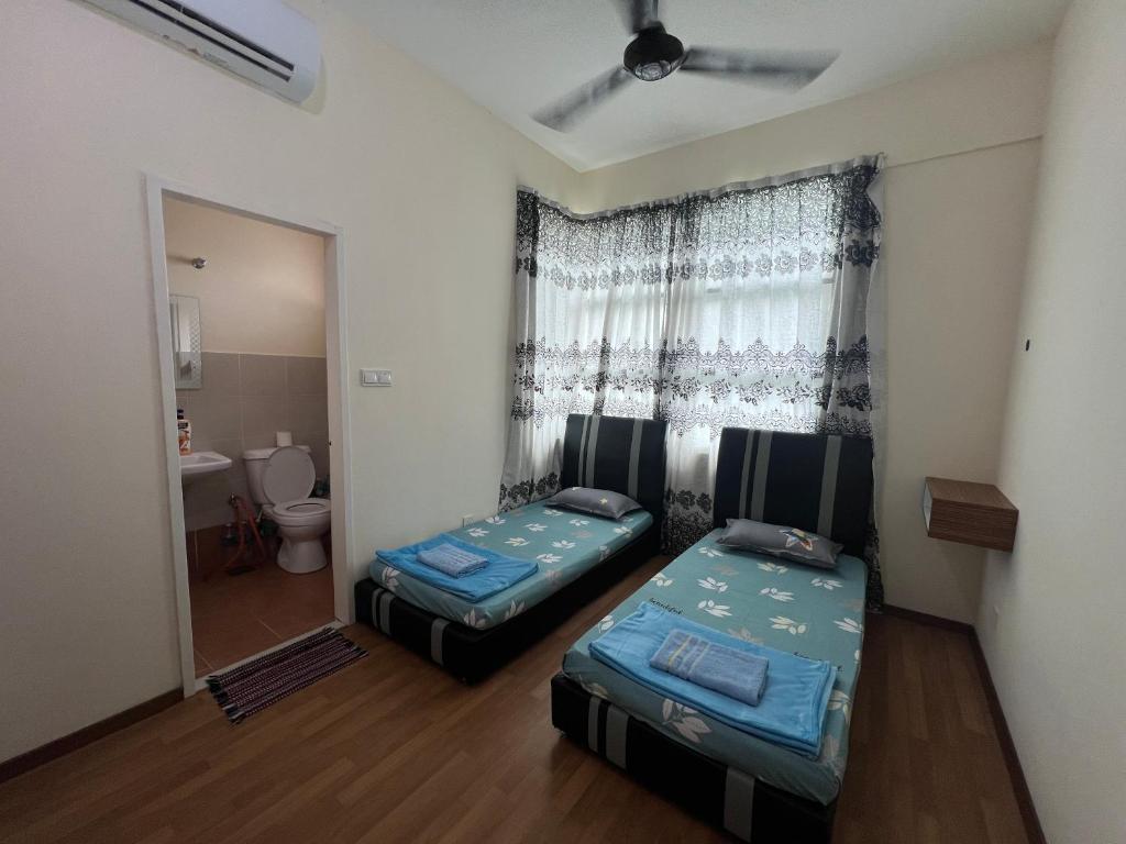 a room with two beds and a window with a toilet at Sandakan Homestay & Backpackers in Sandakan