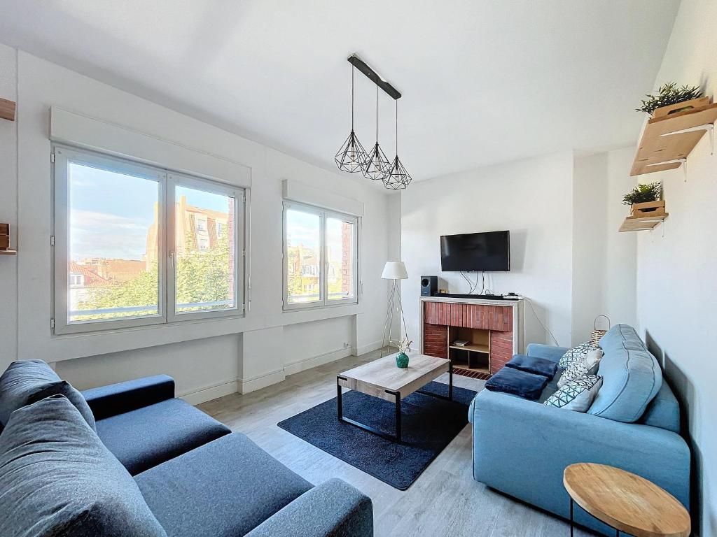 - un salon avec deux canapés bleus et une télévision dans l'établissement Appartement Dunkerque hyper centre, à Dunkerque