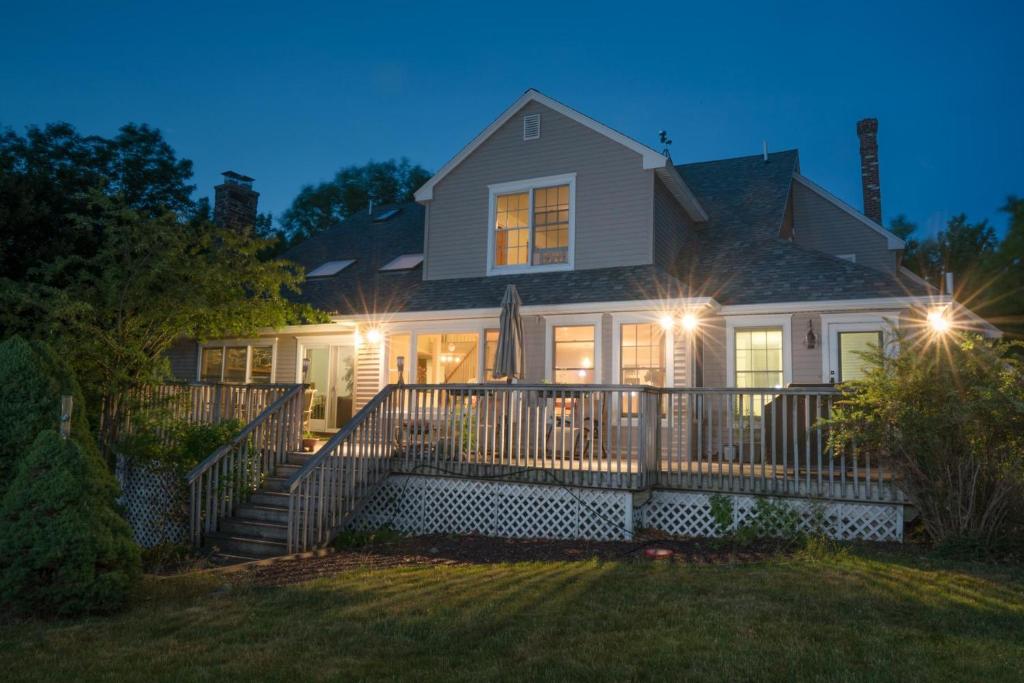 une maison avec des lumières sur la terrasse couverte avant la nuit dans l'établissement Strawberry Hill, à Bar Harbor