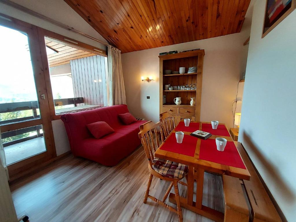 un salon avec une table et un canapé rouge dans l'établissement Studio divisible pour 4 personnes, centre station, animaux admis - FR-1-353-103, à La Plagne Tarentaise