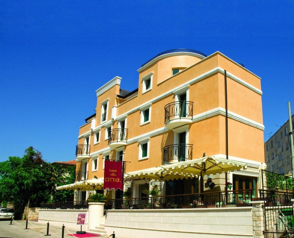 een groot oranje gebouw met een paraplu ervoor bij Hotel Villa Cittar in Novigrad Istria