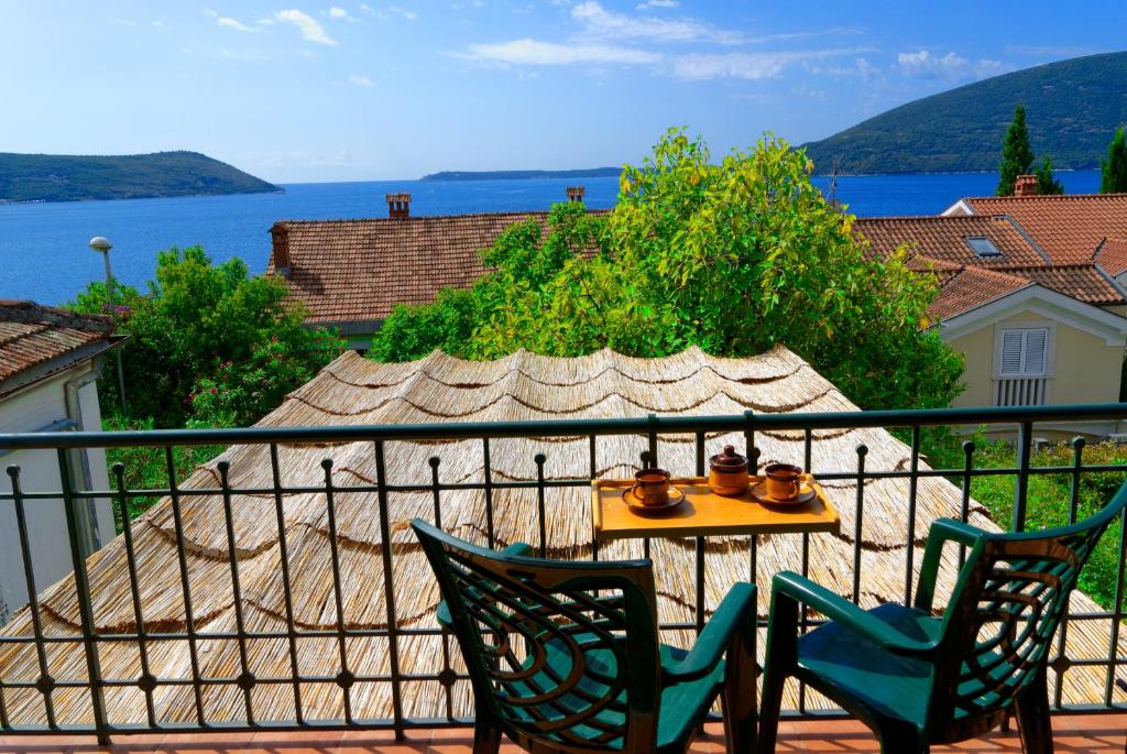 a table and chairs on a balcony with a view of the water at Casa Boka Apartments in Herceg-Novi