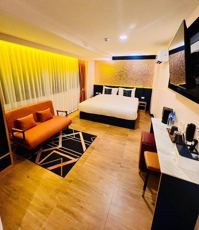 a bedroom with a bed and a couch and a chair at Emiri Hotel - Nana Bangkok in Bangkok