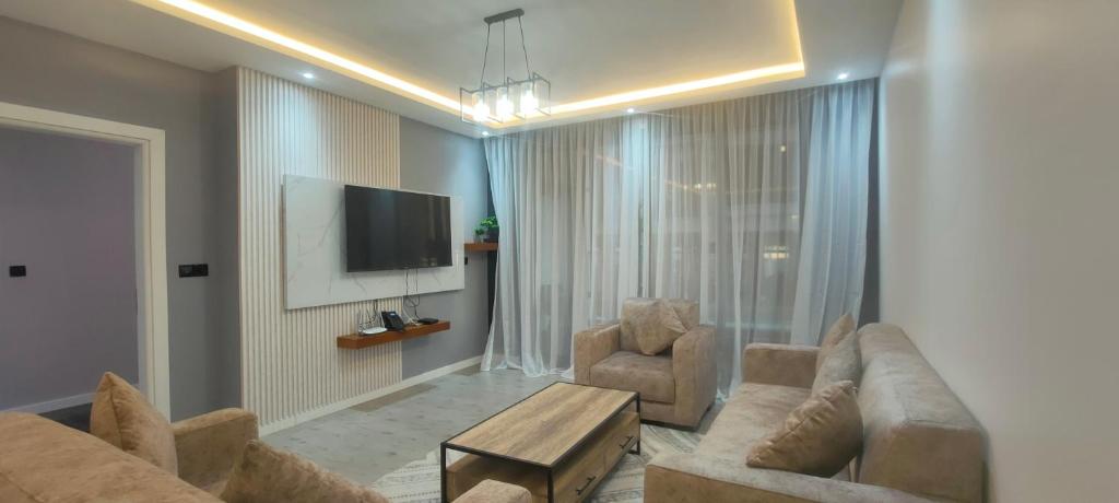 a living room with a couch and two chairs and a tv at Premium apart avec billard et piscine in Yaoundé