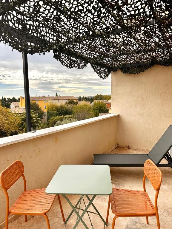 une table et des chaises sur un balcon avec vue dans l'établissement Le Cœur du Village, à Sainte-Cécile-les-Vignes