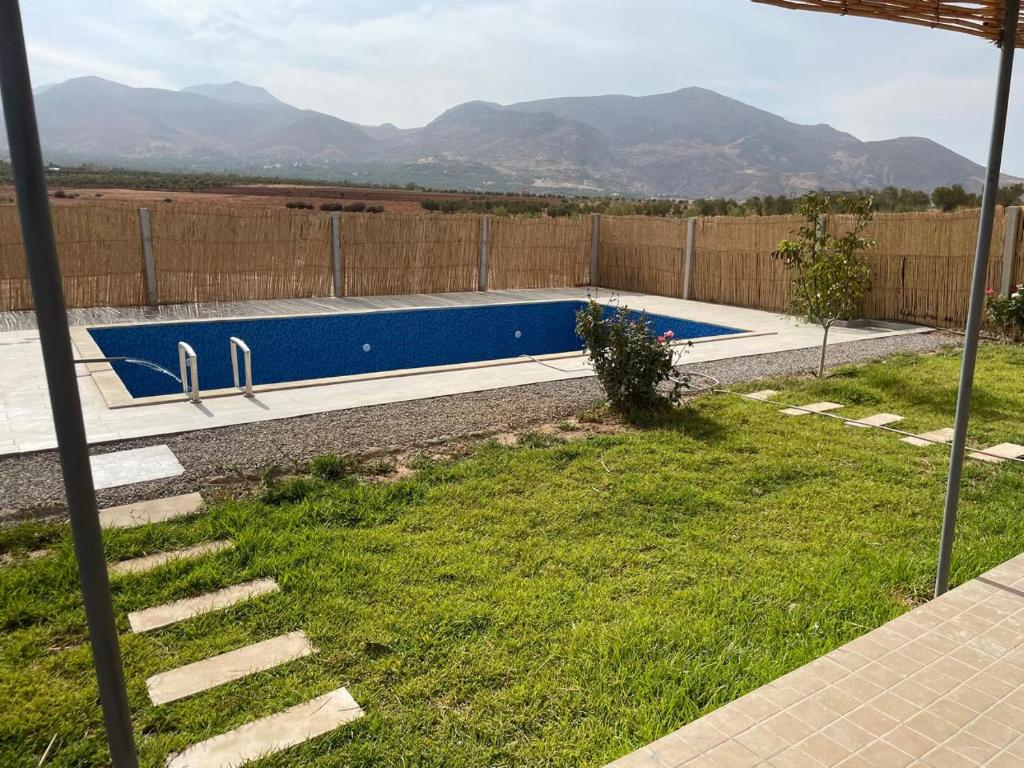 a swimming pool in a yard with mountains in the background at Ferme Jnan Al Yassmine in Taza
