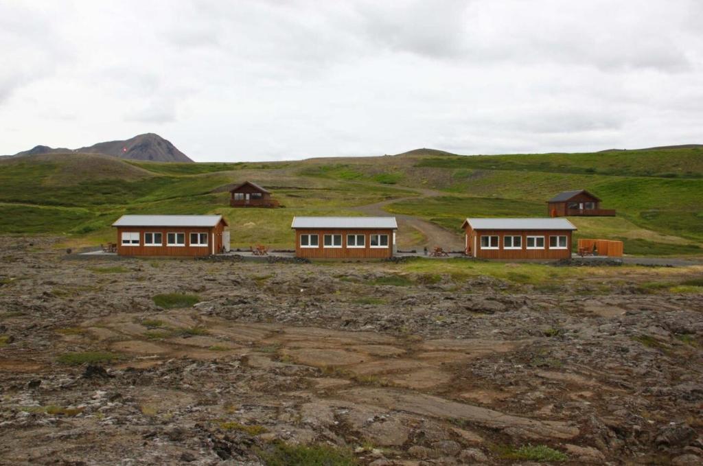 Dos casas en un campo con montañas al fondo en Hlid Bed and Breakfast, en Myvatn