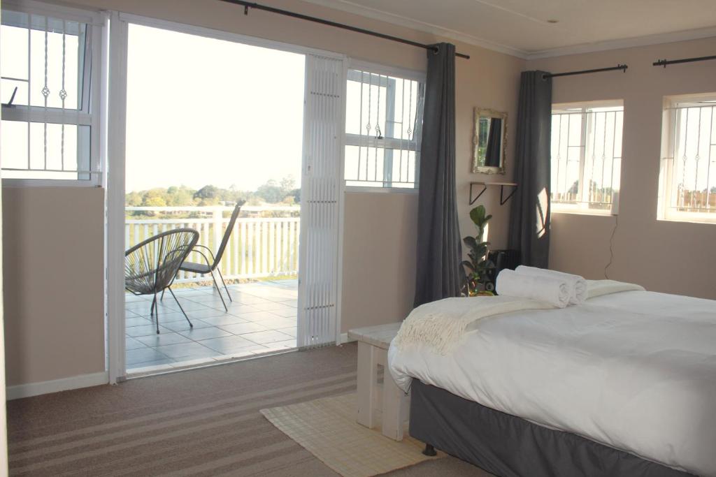 a bedroom with a bed and a balcony with a chair at Fever Tree Cottage in Winston Park