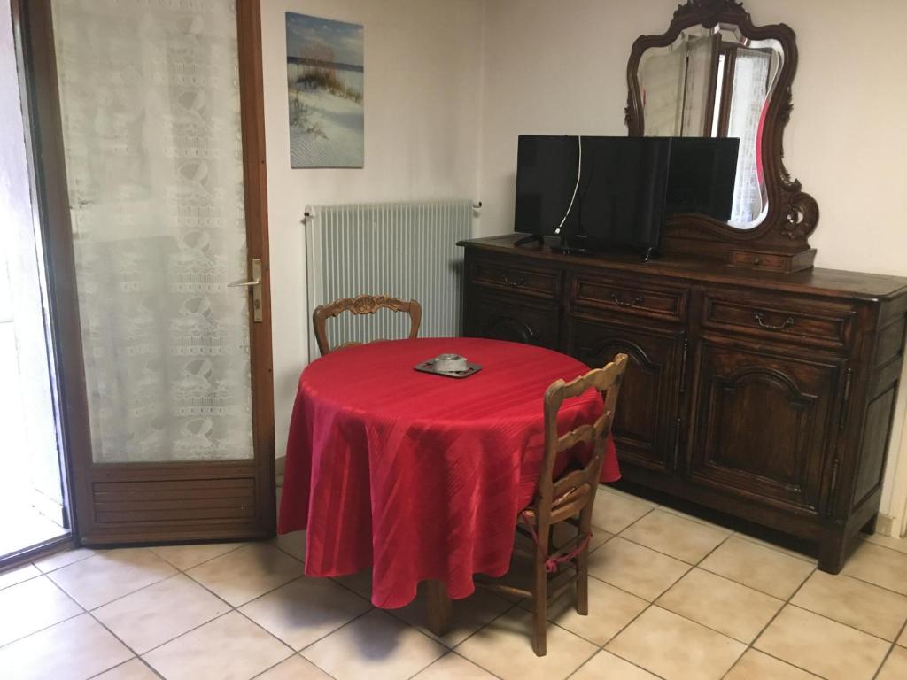 une table avec un tissu de table rouge et une télévision dans l'établissement Jean pierre, à Valence