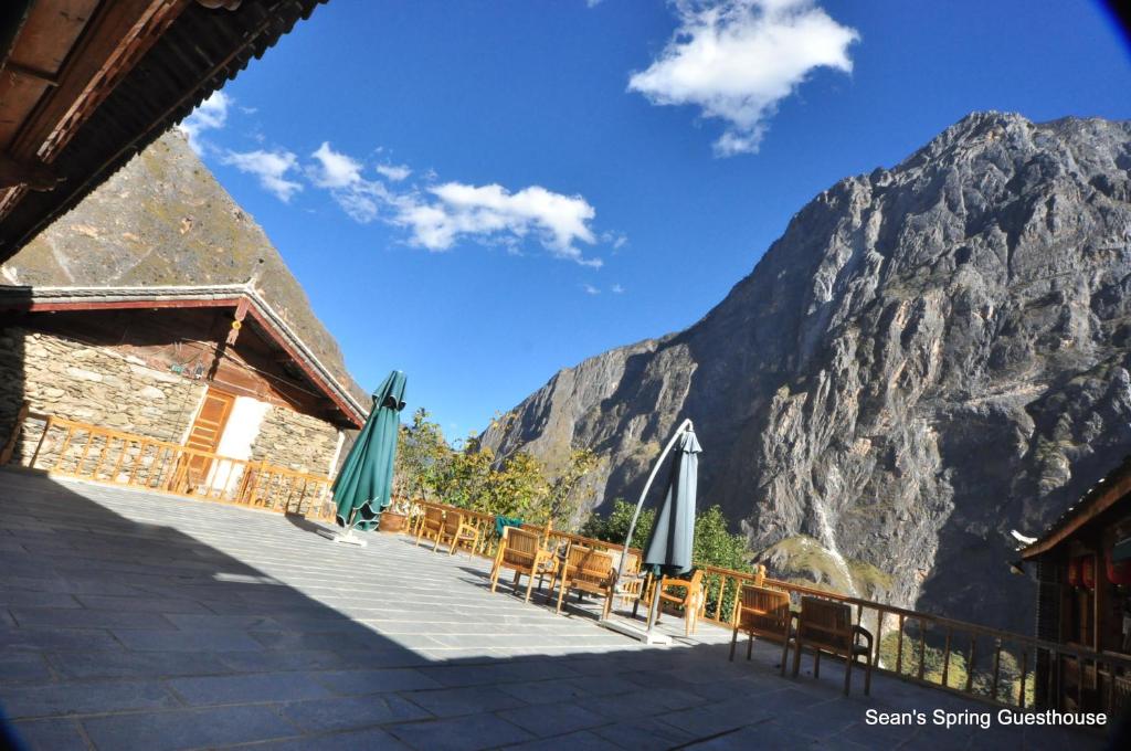 un patio con sillas y sombrillas frente a una montaña en Tiger Leaping Gorge Sean’s Spring Guesthouse, en Shangri-La