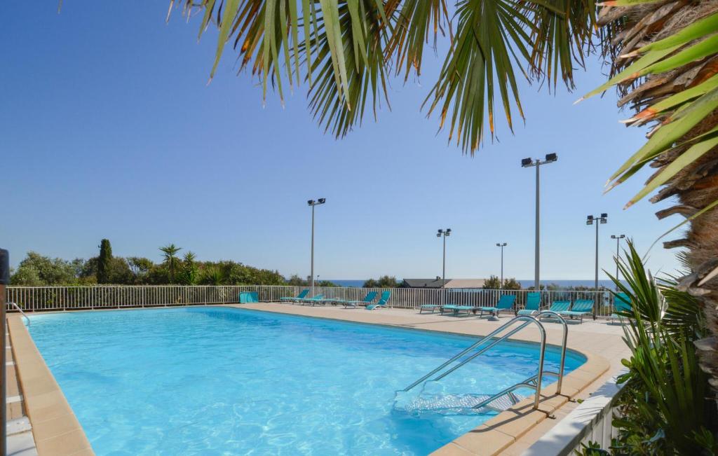 une grande piscine avec de l'eau bleue et des palmiers dans l'établissement Beautiful Home In Cervione With Wifi, à Cervione