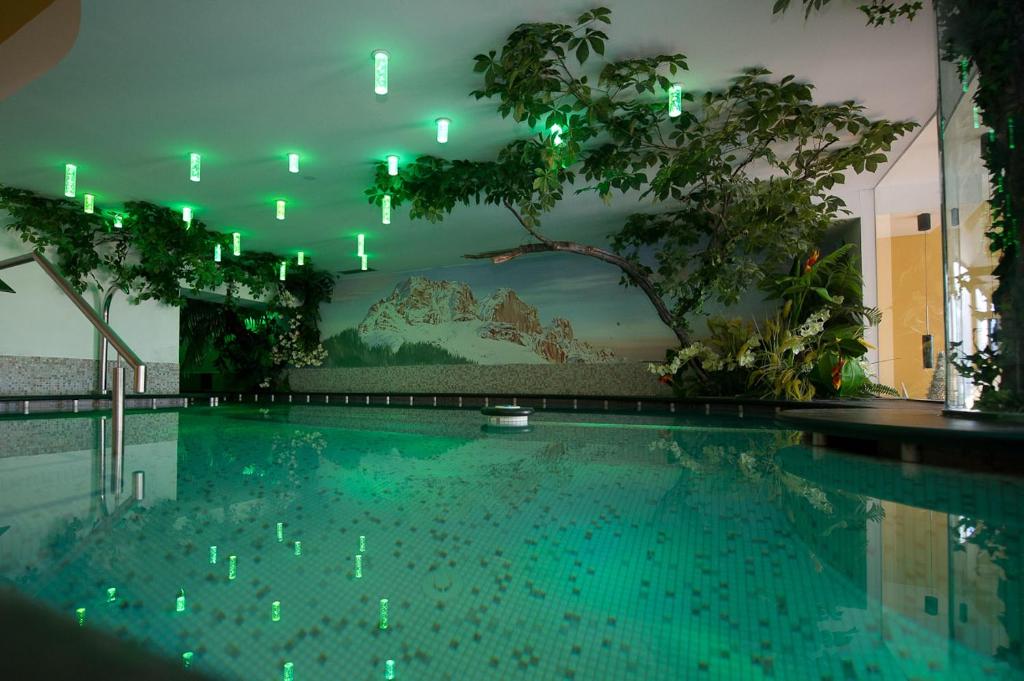 a swimming pool with green lights in a building at Family & Wellness Hotel Fontana in Vigo di Fassa