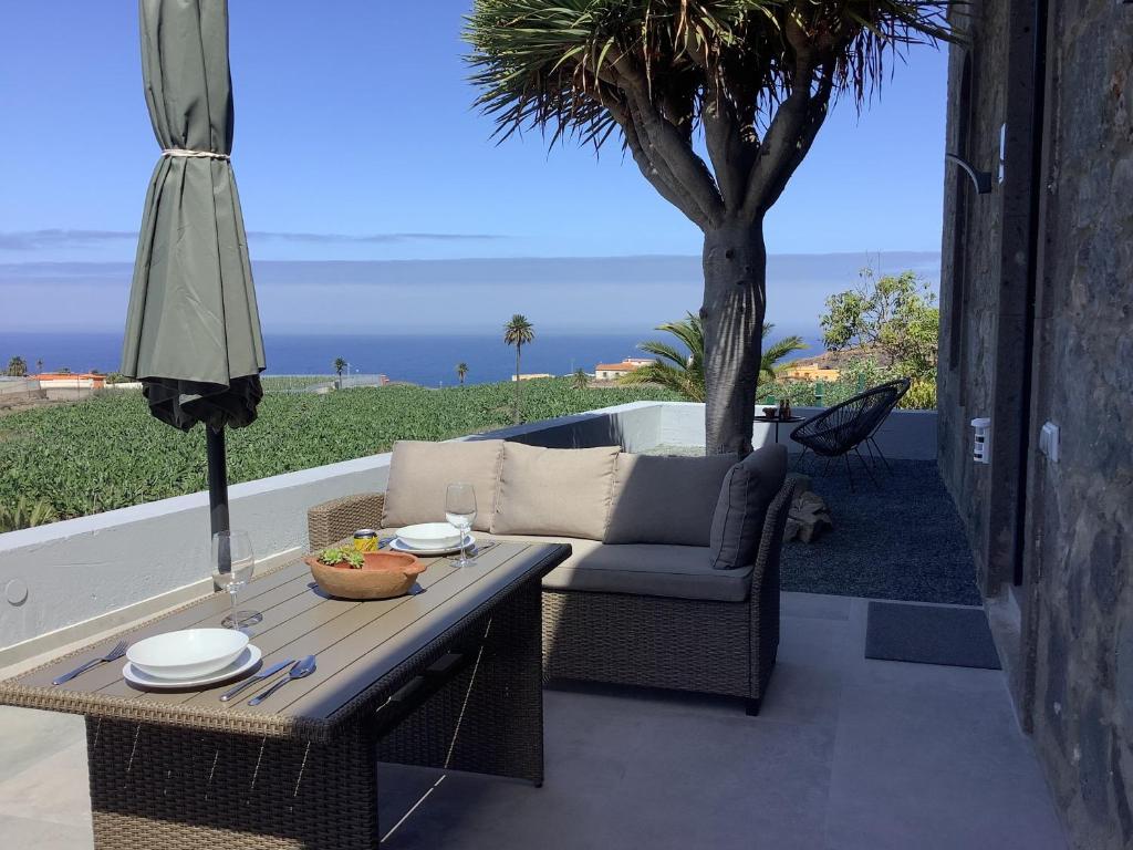 a patio with a table and a couch and a tree at Villa Alpispa in Las Palmas de Gran Canaria