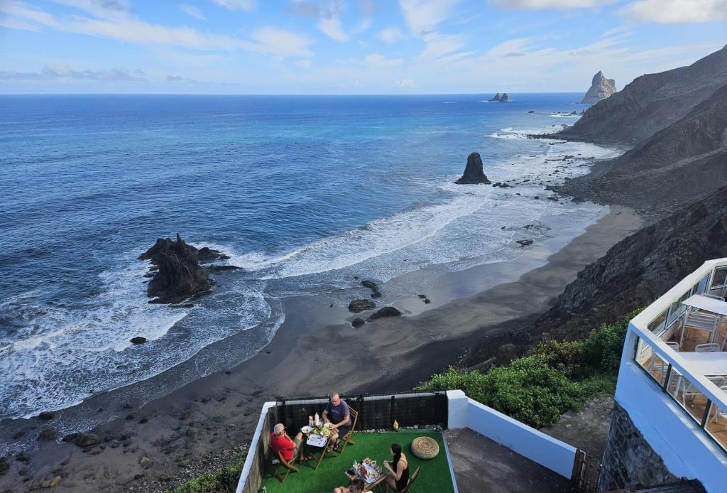 a group of people sitting on a cliff overlooking the ocean at Anaga Playa Benijo 2 Paraíso Rural Trail-Beach in Almáciga