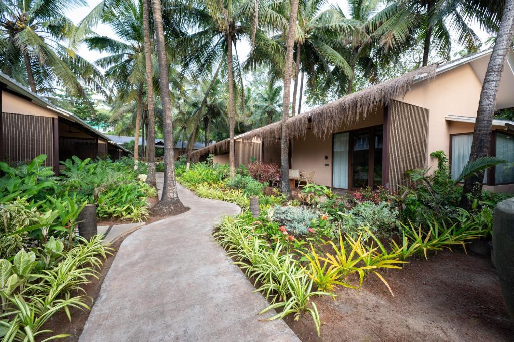a walkway in front of a building with palm trees at Palma Beach Resort in Mandrem