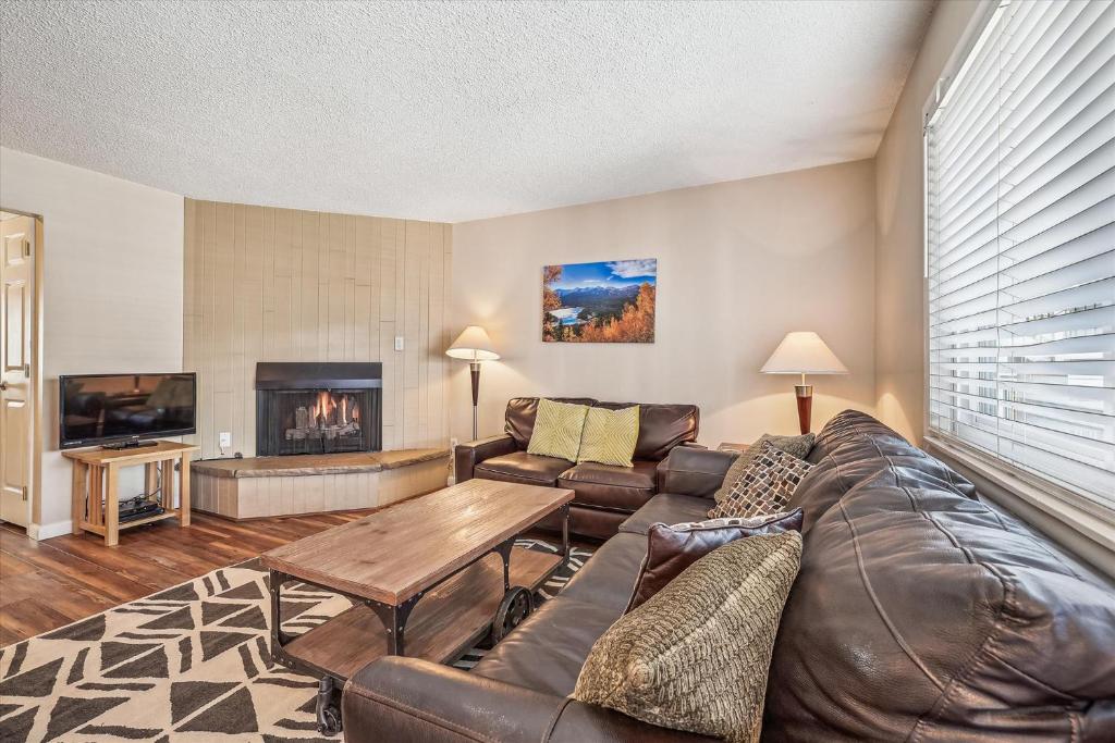 a living room with a leather couch and a fireplace at Tannhauser 214 in Breckenridge