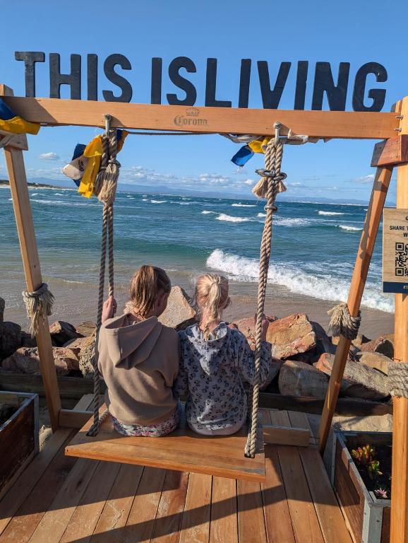 two people sitting on a swing at the beach at Dune Whispers in Jeffreys Bay