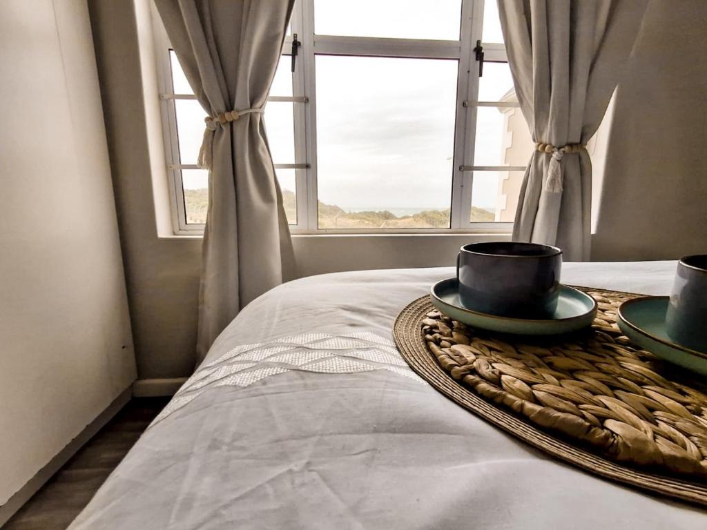 a room with a bed with two bowls and a window at Dune Whispers in Jeffreys Bay