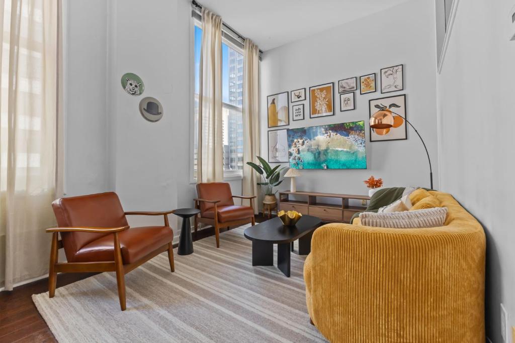 a living room with a yellow couch and chairs at Downtown Indy 2BR - Stadium, Convention - Arcade Games - Skywalk in Indianapolis