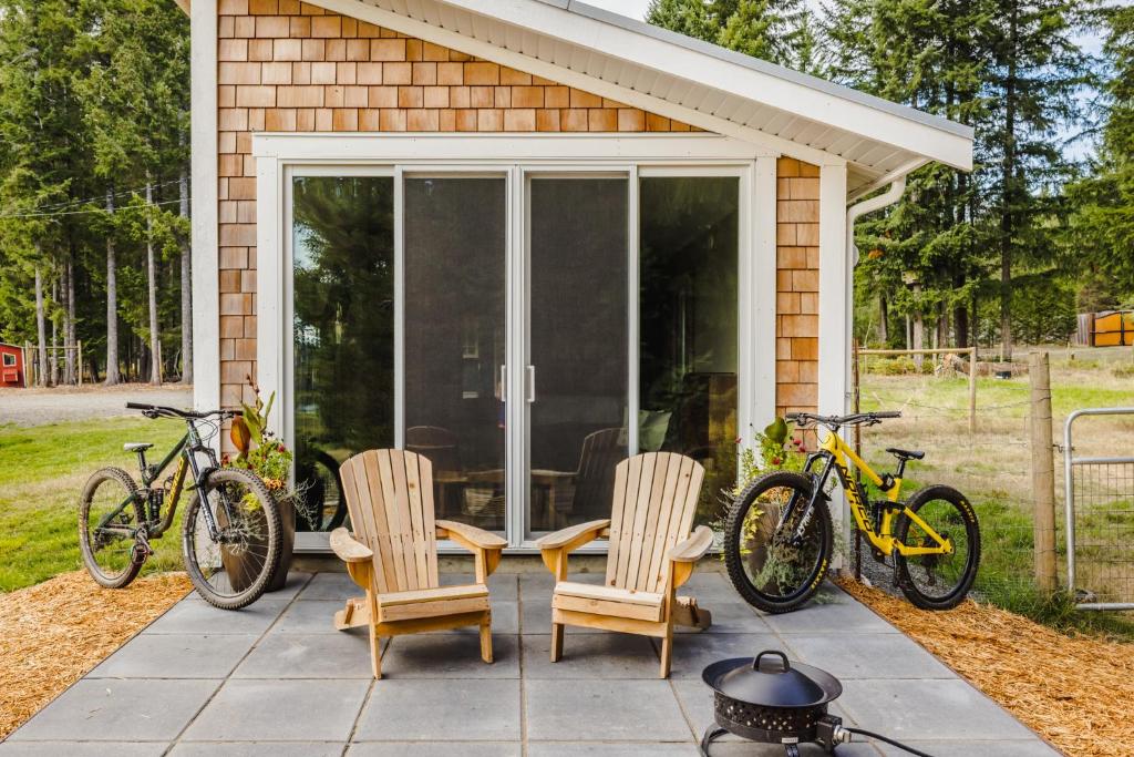 MervilleTiny house & Sauna on Lakefront Farm Oasis的露台上摆放着两把椅子，外面停着两辆自行车。