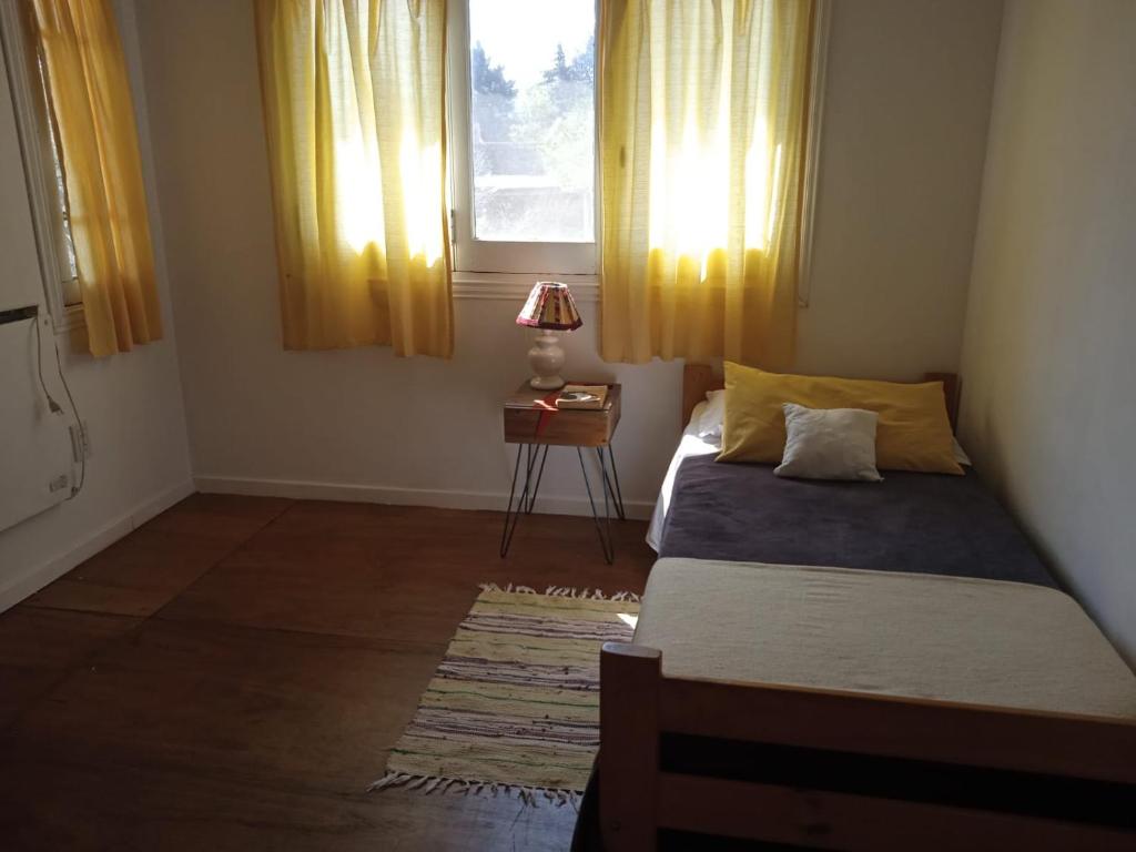 a bedroom with a bed and a window with yellow curtains at Chalet Las Doritas in La Cumbre