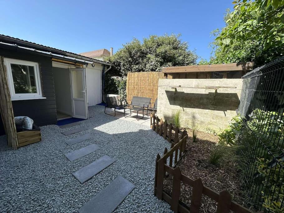 une cour avec une clôture et une terrasse avec un bâtiment dans l'établissement Maison 2 pièces Ouistreham, à Ouistreham