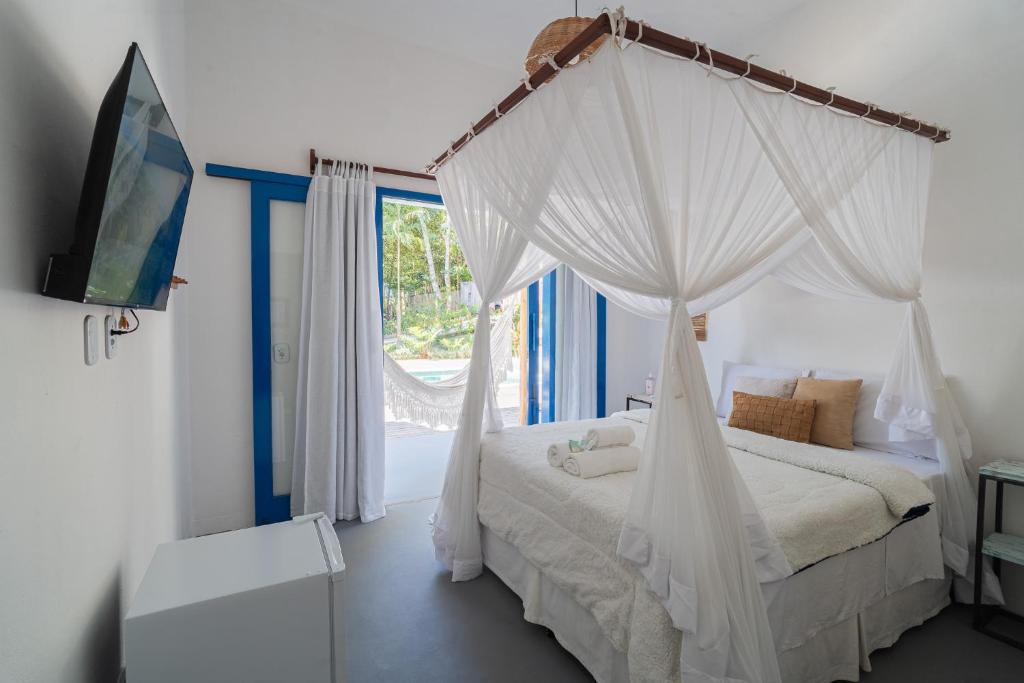 a bedroom with a canopy bed and a window at Casa Angelina in Trancoso