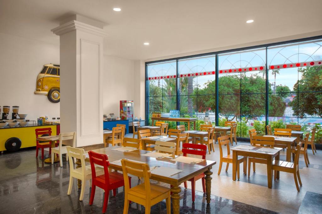 a restaurant with tables and chairs and a large window at IC Hotels Santai Family Resort - Kids Concept in Belek