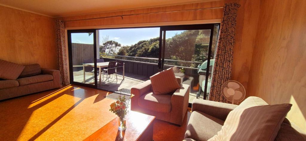 Una sala de estar con un sofá y una ventana grande. en Rimu Studio holiday accommodation, en Raglan