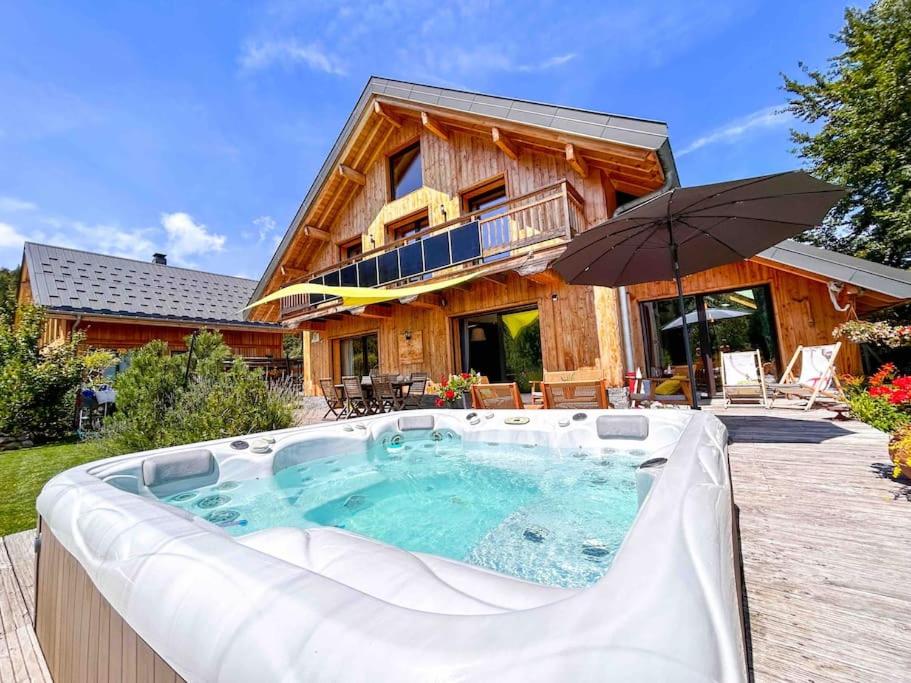 un grand bain à remous en face d'une maison dans l'établissement Le Chalet du Lys avec jacuzzi, à Les Déserts