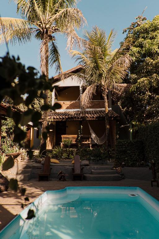 une piscine devant une maison avec des palmiers dans l'établissement FLATS COMFORT- Melhor CUSTOXBENEFÍCIO na charmosa Vila de São Jorge, Goiás, à Sao Jorge