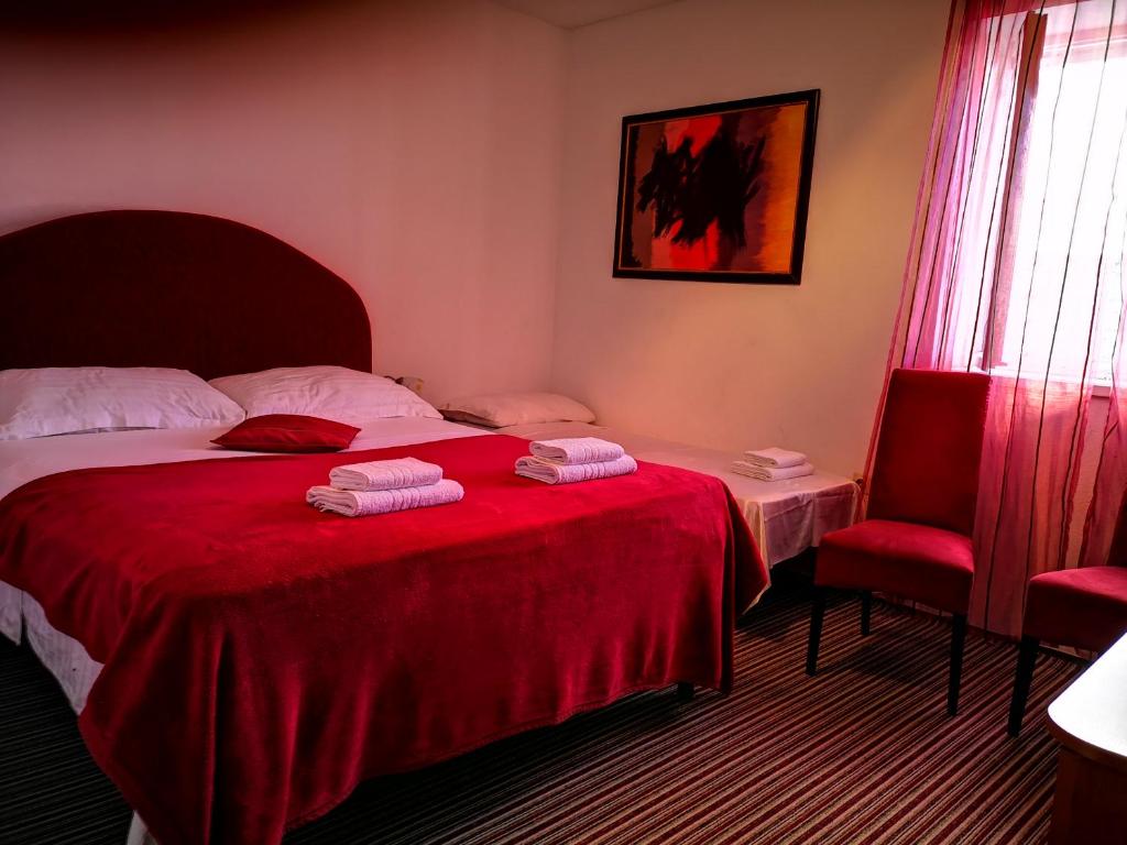 a bedroom with a red bed with two towels on it at Heritage Bella Vista in Trogir