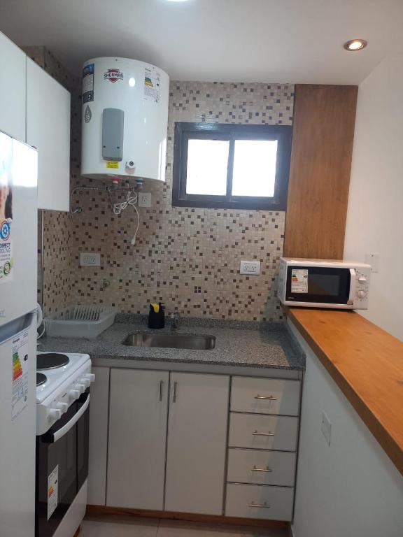 a kitchen with white cabinets and a sink and a window at Depto 41 in Santa Teresita