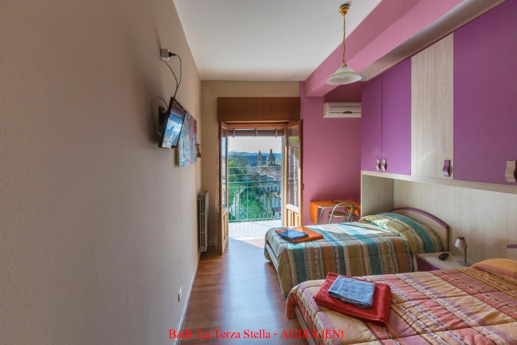 a hotel room with two beds and a balcony at Casa Albergo La Terza Stella in Agira