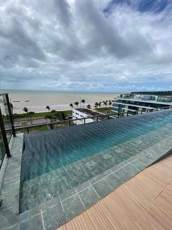 een zwembad met uitzicht op het strand bij sol flat cabo branco 50 metros do mar in João Pessoa