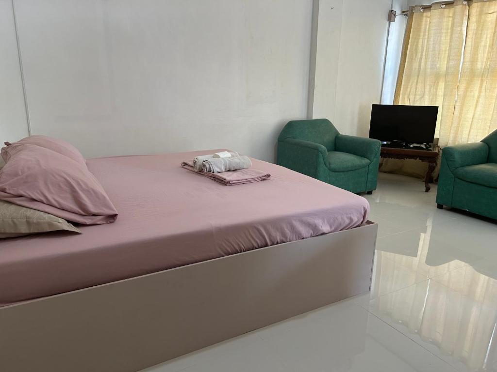 ein Bett in einem Zimmer mit zwei grünen Stühlen in der Unterkunft En Pensionne Pension House in Iloilo City