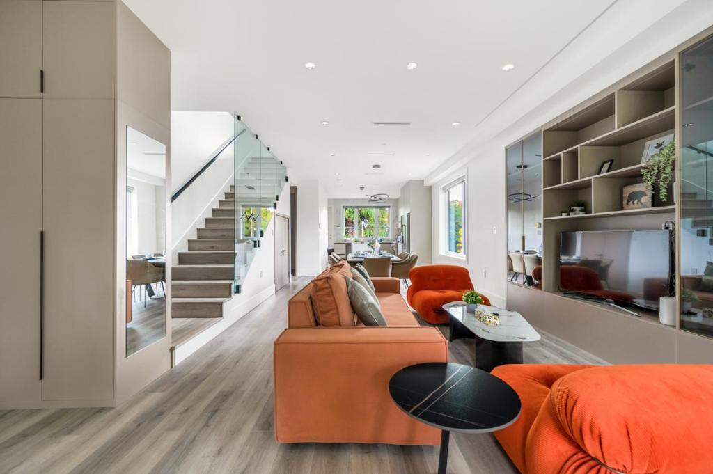 ein Wohnzimmer mit einem orangenen Sofa und einer Treppe in der Unterkunft Charming and Modern Retreat in Vancouver Trendy 42nd Avenue Neighbourhood in Vancouver