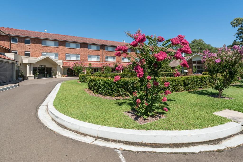 保尔罕希尔斯Mary MacKillop Spirituality Centre Baulkham Hills的院子里有粉红色花的建筑