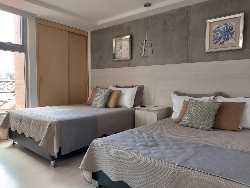 a bedroom with two beds and a window at San Peter Family Suites in Medellín