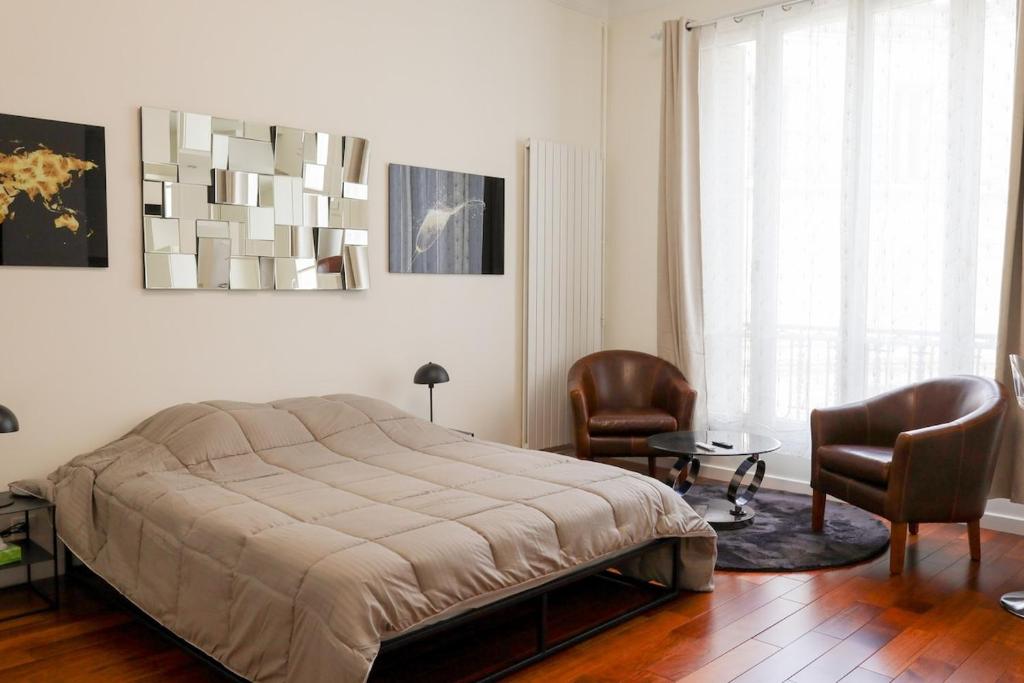une chambre avec un lit, deux chaises et une table dans l'établissement Nouveau studio au cœur de l'Opéra - Paris 1er, à Paris