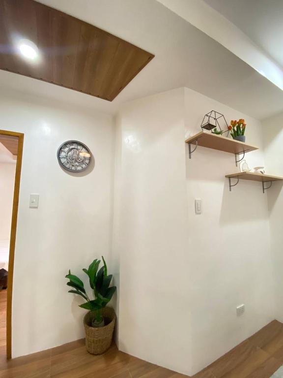 a room with a white wall with a clock and a plant at RHM homestay in Naga