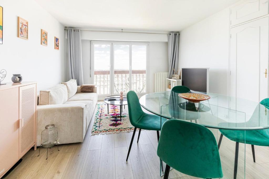- un salon avec une table en verre et des chaises vertes dans l'établissement Appartement Élégant à Montmartre, à Paris