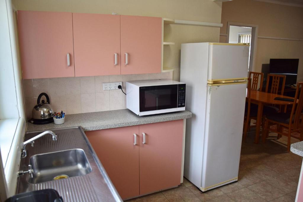 Una cocina con un refrigerador blanco y un microondas. en Clarkes Flat 2, en South West Rocks