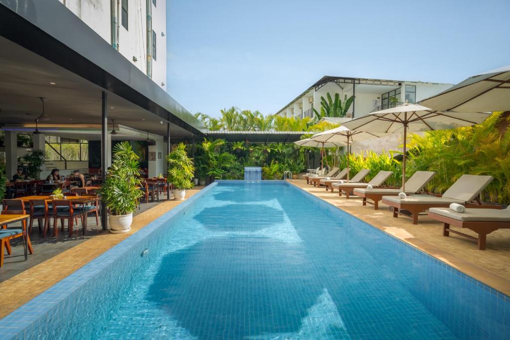 a large swimming pool with lounge chairs and tables at Onederz Siem Reap in Siem Reap