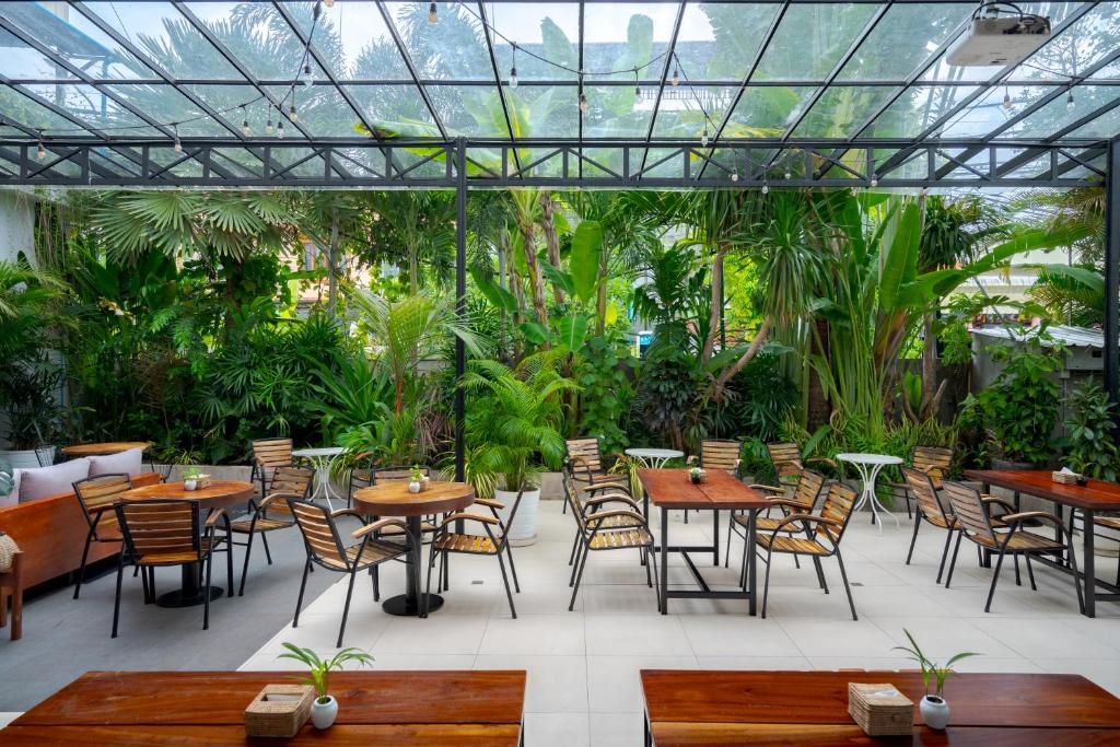 a restaurant with tables and chairs and plants at Onederz Siem Reap in Siem Reap