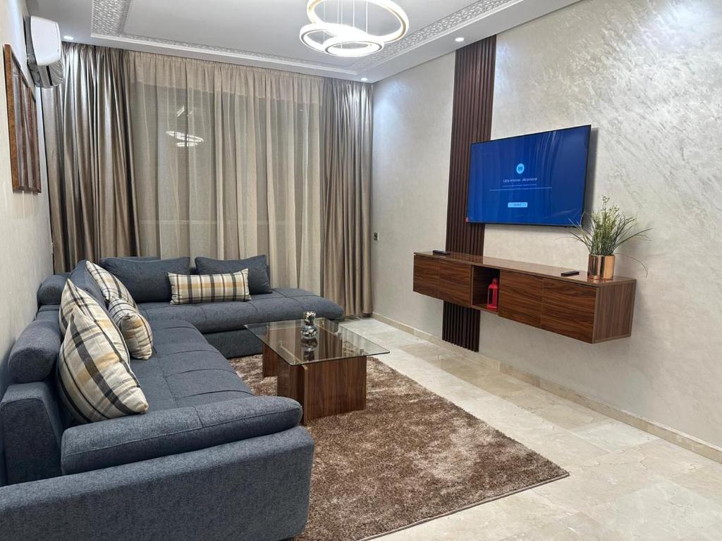 a living room with a blue couch and a flat screen tv at appartement Sf in Casablanca