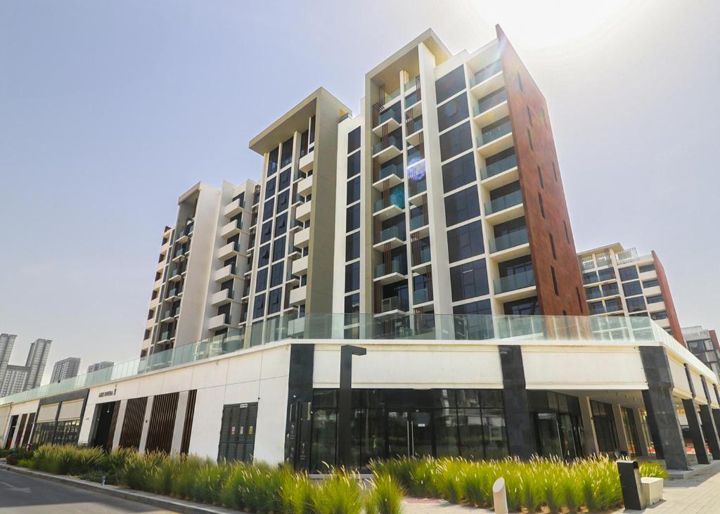 Escape24 Stylish Studio Azizi Riviera 8 Meydan one Dubai في دبي: مبنى كبير شبابيكه زجاجيه على شارع